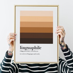 May include: A gold framed print with a brown and beige striped background. The print features the word "linguaphile" with its definition: "[ling-gwah-fahyl]  böredönyms (n.) a lover of languages and words."