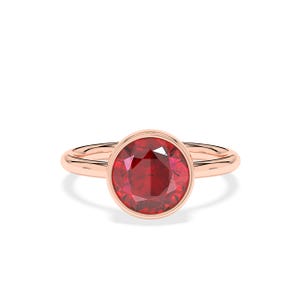 Könnte beinhalten: Ein roségoldener Ring mit einem großen, runden, facettierten Rubin-Edelstein. Der Rubin hat eine tiefrote Farbe und ist in einer Zargenfassung gefasst. Das Band ist glatt und poliert.