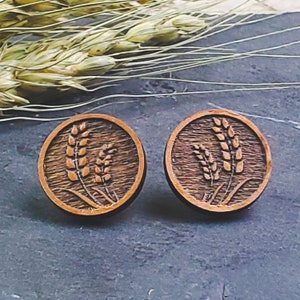 May include: A pair of wooden earrings with a carved wheat design. The earrings are round and have a brown wood finish.
