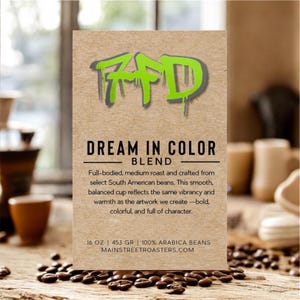 May include: A kraft paper coffee bag with the text "FFD" in green and gray, and "DREAM IN COLOR BLEND" in black. The bag also states the coffee is a medium roast, 16 oz, and made with 100% Arabica beans. Coffee beans are scattered around the bag.