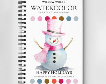 Könnte beinhalten: Ein spiralgebundenes Aquarell-Malbuch mit einer Schneemann-Illustration. Der Schneemann trägt einen rosa Zylinder und Schal und hat Zweigarme. Auf dem Cover steht "Willow Wolfe Watercolor Painting Workbook" und "Happy Holidays".
