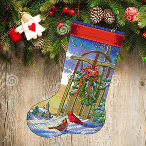 May include: A Christmas stocking with a winter scene featuring a red sled, a snowy village, and two cardinals. The stocking is decorated with a red ribbon and a green wreath.