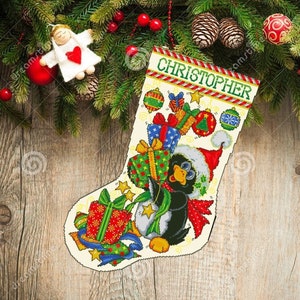 May include: A white Christmas stocking with a penguin holding a gift. The stocking is decorated with red, green, and gold ornaments and the name "CHRISTOPHER" is embroidered on the top.