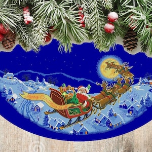 Puede incluir: Una falda de árbol de Navidad azul con una escena de invierno nevada con Santa Claus en su trineo tirado por renos. El texto "Merry Christmas to all" está en una pancarta amarilla.