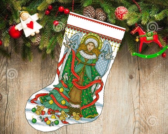 Könnte beinhalten: Ein weißer Weihnachtssocken mit einem grünen, roten und goldenen Engel, der eine Taube und einen Weihnachtsbaum mit Ornamenten hält. Der Socken hat einen weißen und blauen gestreiften Bund.