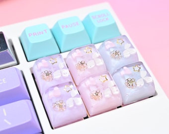 May include: A close-up of a white keyboard with pastel blue and purple keys. The keys have a floral and star design with gold accents. The keys are labeled "Print", "Pause", and "Scroll Lock".