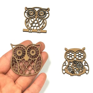 May include: Three wooden owl cutouts with intricate designs. The owls are brown and have different patterns on their bodies.