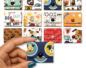 May include: A collection of small, rectangular paper envelopes featuring various dog-themed patterns, including paw prints, bones, and cartoon dog faces. Each envelope is secured with a single, centered, round bead button in assorted colors.