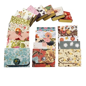 May include: A set of 14 small, square boxes with floral patterns. The boxes are made of cardboard and have a flap that closes with a button. The boxes are arranged in two rows, with seven boxes in each row. The boxes are all different colors and patterns, and they are all decorated with flowers.