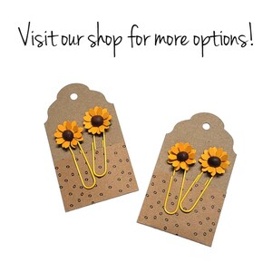 May include: Two sets of yellow paper clips with sunflower embellishments. Each set is displayed on a brown tag with a white polka dot pattern.