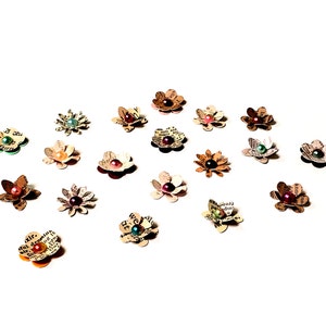 Könnte beinhalten: Eine Auswahl an Papierblumen mit Perlenmitten in verschiedenen Farben, darunter Grün, Rot, Pink und Braun. Die Blumen sind aus Recyclingpapier gefertigt und haben einen Vintage-Look.