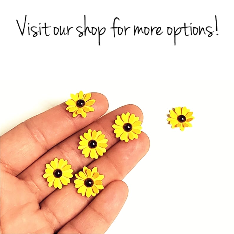 Op de afbeelding: Zes gele papieren bloemen met bruine centra. De bloemen zijn gerangschikt op een hand.