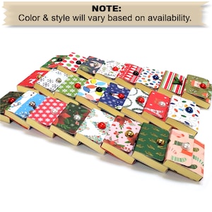 May include: A collection of small, rectangular boxes with various Christmas-themed patterns. Each box has a gold-colored base and a patterned lid with a decorative button closure. The patterns include snowflakes, Christmas lights, and holly.