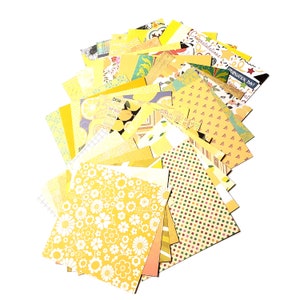 May include: A stack of yellow patterned scrapbook paper with various designs, including lemons, polka dots, and flowers. The paper is perfect for crafting and scrapbooking projects.
