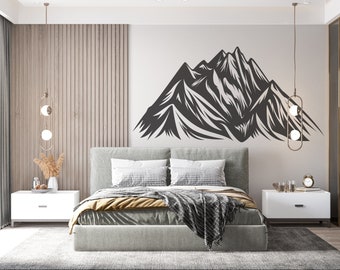 May include: A bedroom interior with a modern bed, two white nightstands, and a black and white mountain range wall decal. The bed has a gray headboard, a gray and white patterned throw blanket, and a yellow throw pillow.