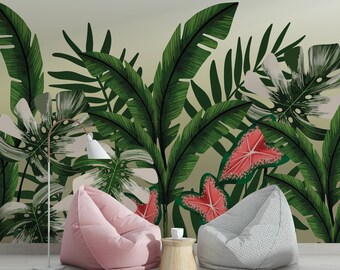 Könnte beinhalten: Zwei Sitzsäcke, einer rosa und einer grau, stehen vor einer Wandmalerei, die eine tropische Dschungelszene mit großen grünen Blättern und rosa Blüten zeigt. Ein kleiner Holztisch mit einer weißen Tasse steht zwischen den Sitzsäcken.