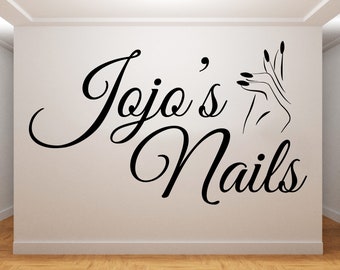 May include: Black and white wall decal with the text "Jojo's Nails" in a cursive font. A stylized image of a hand with manicured nails is to the right of the text.