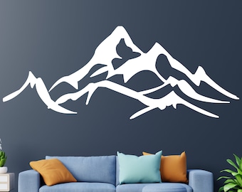 May include: White silhouette of a mountain range on a dark blue wall. The mountain range is stylized with a jagged peak and flowing lines. The silhouette is a wall decal, perfect for adding a nature-inspired touch to a home.
