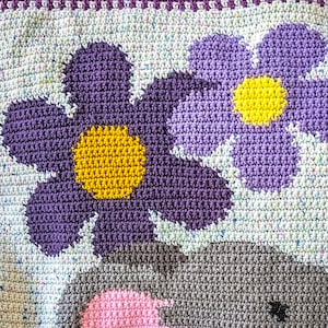 May include: Crocheted blanket with a purple and yellow flower design. The blanket is made with a variety of colors and textures.