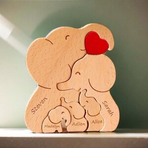 Peut inclure: Puzzle en bois en forme de famille d'&eacute;l&eacute;phants avec un c&oelig;ur rouge sur l'&eacute;l&eacute;phant du haut. Les &eacute;l&eacute;phants sont &eacute;tiquet&eacute;s avec les noms "Steven", "Sarah", "Madelyn", "Adien" et "Alice".