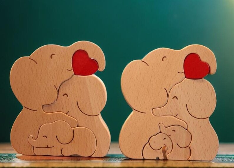 Peut inclure: Deux familles d'&eacute;l&eacute;phants en bois, chacune compos&eacute;e de trois &eacute;l&eacute;phants, tiennent des c&oelig;urs rouges. Les &eacute;l&eacute;phants sont empil&eacute;s les uns sur les autres, le plus petit en bas.