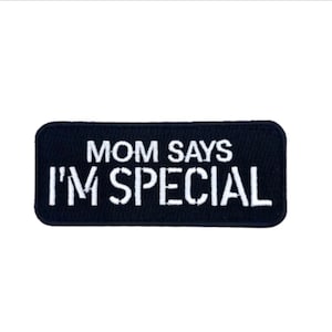 May include: A rectangular embroidered patch with a dark navy blue background and white stitched text that reads MOM SAYS I'M SPECIAL. The patch features rounded corners and a clean, bold sans-serif font style for the lettering.