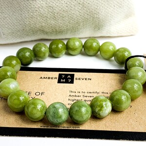 May include: A green jade stone bracelet with a brown card that reads "Amber Seven" and "This is to certify: this is Amber Seven highest quality".
