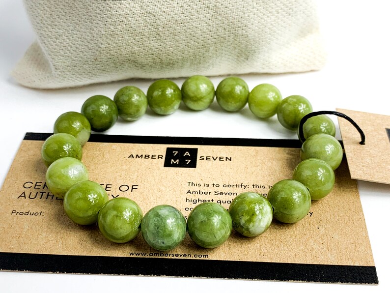 May include: A green jade stone bracelet with a brown card that reads "Amber Seven" and "This is to certify: this is Amber Seven highest quality".