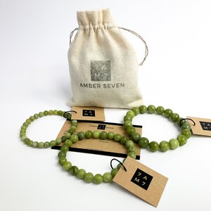 May include: Three green jade stone bracelets with brown paper tags that say "Amber Seven" and a small white drawstring bag with the same text.