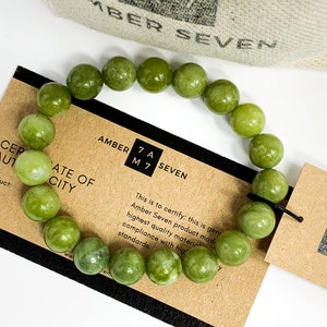 May include: A green jade stone bracelet with a brown card that reads "Amber Seven" and "Certificate of Authenticity".