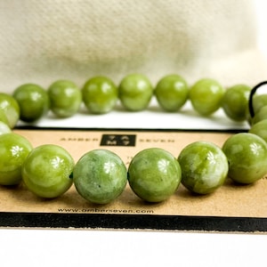 May include: A green jade stone bracelet with a dark brown card that says "Amber Seven" and "www.amberseven.com".