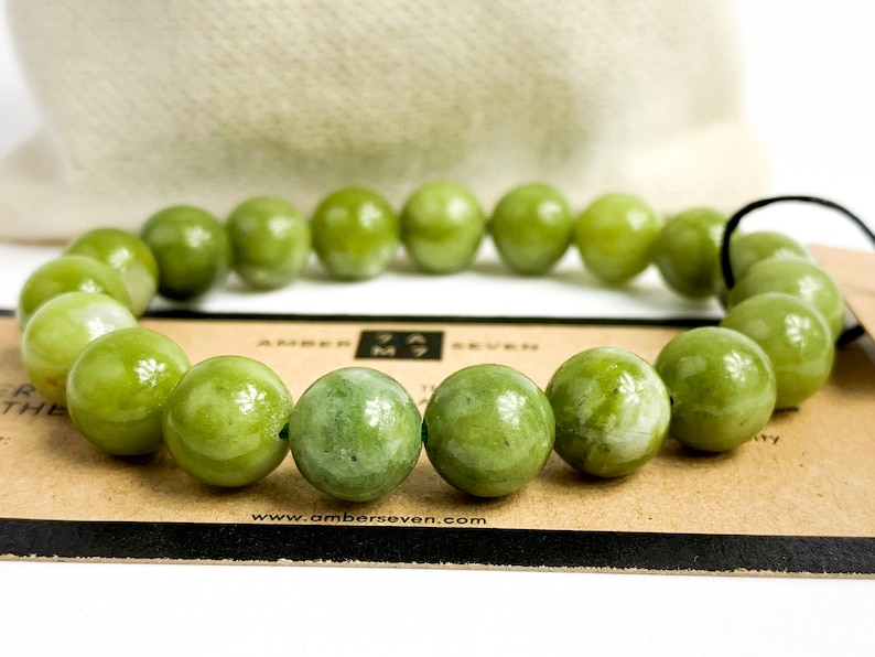 May include: A green jade stone bracelet with a dark brown card that says "Amber Seven" and "www.amberseven.com".
