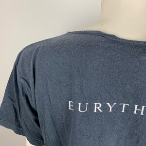 May include: A dark grey t-shirt with the word "EURYTHM" printed in white on the back.