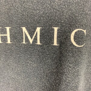 May include: Close-up of a dark grey fabric with the word "HMIC" printed in white.