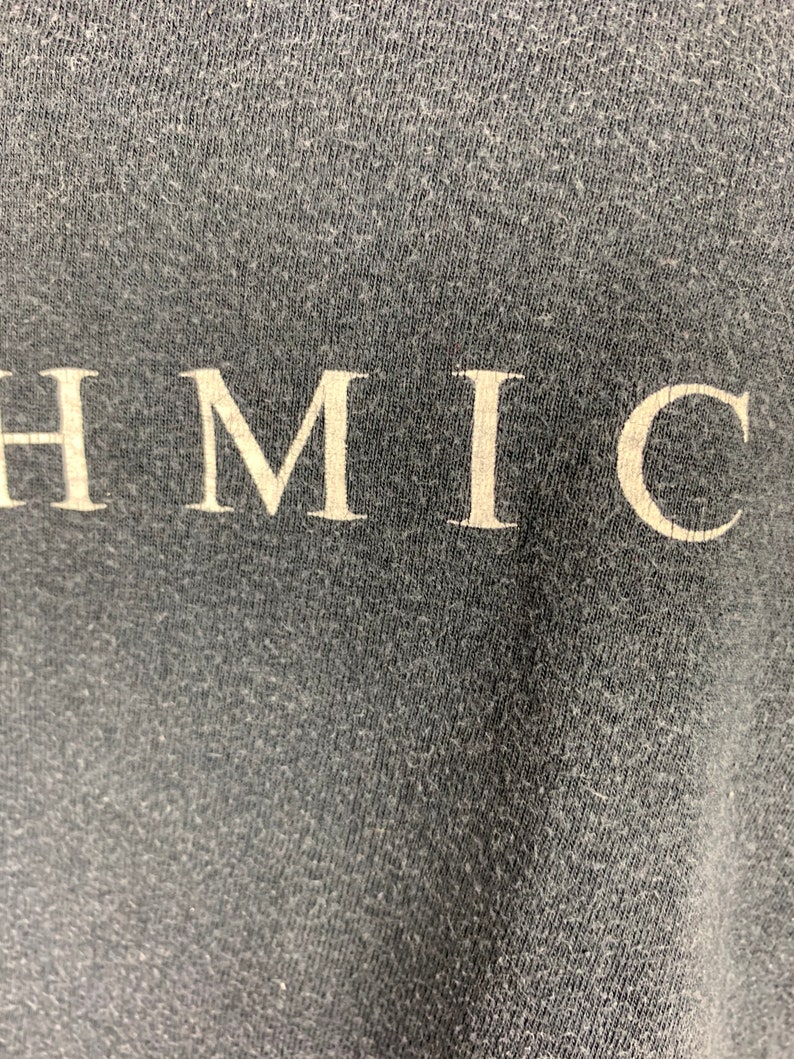 May include: Close-up of a dark grey fabric with the word "HMIC" printed in white.