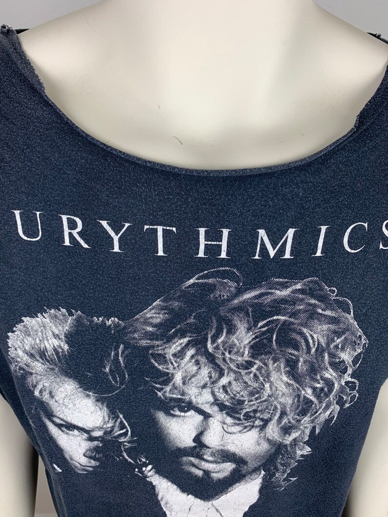 May include: A black t-shirt with a white print of the band Eurythmics. The print features a black and white image of the band members.