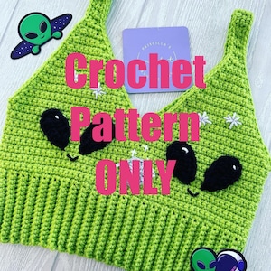 Könnte beinhalten: Ein limettengrünes Häkeltop mit schwarzen Alienaugen und weißen Sternakzenten. Der Text "Crochet Pattern ONLY" ist über dem Top überlagert. Zwei Alien-Aufkleber und ein lila Etikett sind ebenfalls sichtbar.