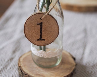 May include: A clear glass bottle with a wooden slice attached to it. The wooden slice has the number "1" burned into it. The bottle is sitting on a wooden slice.