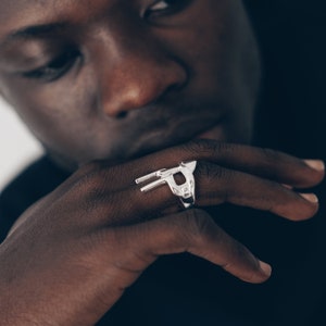 Peut inclure: Une bague en argent avec un motif g&eacute;om&eacute;trique repr&eacute;sentant une t&ecirc;te d'animal stylis&eacute;e.