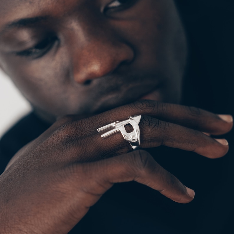 Peut inclure: Une bague en argent avec un motif g&eacute;om&eacute;trique repr&eacute;sentant une t&ecirc;te d'animal stylis&eacute;e.