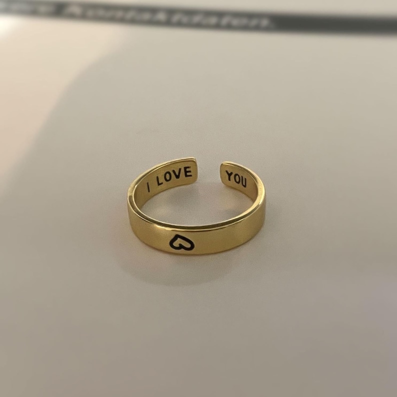 May include: A gold adjustable ring with the words "I LOVE YOU" engraved on the band. A small heart is engraved on the inside of the ring.
