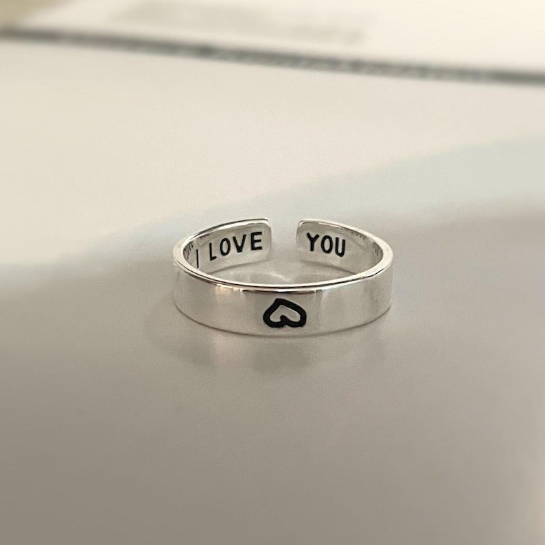 May include: Silver adjustable ring with the words "I Love You" and a heart engraved on the band.