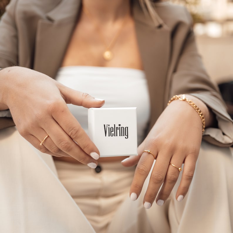Pu&ograve; includere: Una scatola bianca con la scritta "Vielring" stampata su di essa. La scatola &egrave; tenuta da una persona che indossa una giacca marrone e una maglia bianca.