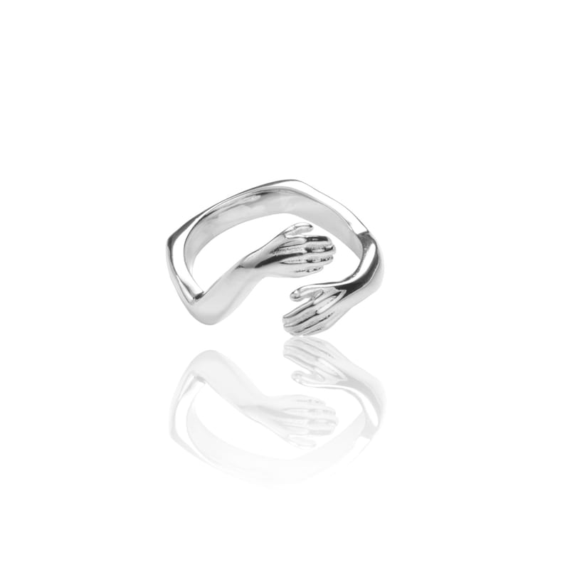 Pu&ograve; includere: Un anello d'argento con due mani intrecciate in un abbraccio. L'anello &egrave; progettato per assomigliare a due braccia che si abbracciano.