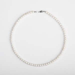 May include: A white pearl necklace with a silver clasp.