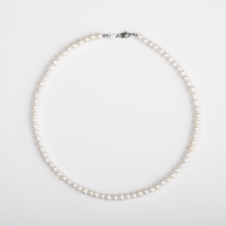 May include: A white pearl necklace with a silver clasp.