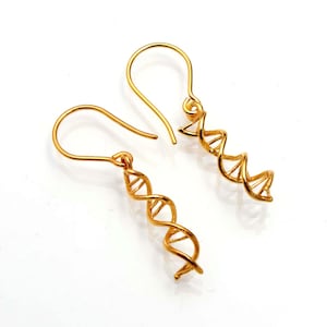 Könnte beinhalten: Ein Paar goldfarbene Ohrringe mit einem Doppelhelix-Design. Die Ohrringe sind aus Metall und haben einen schlichten, eleganten Stil.