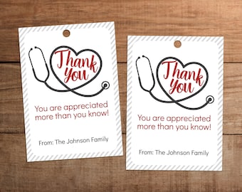 May include: Two white gift tags with a grey and white striped background. Each tag has a black and grey stethoscope with a red heart that says "Thank You". The text below the heart says "You are appreciated more than you know!" and "From: The Johnson Family".
