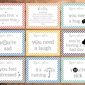 May include: A set of nine rectangular cards with colorful striped borders. Each card features black text and icons, including phrases like Open when you first receive this, you need a hug, you're sad, you need a laugh, having a bad day, feel stressed, it's raining, and you're sick.