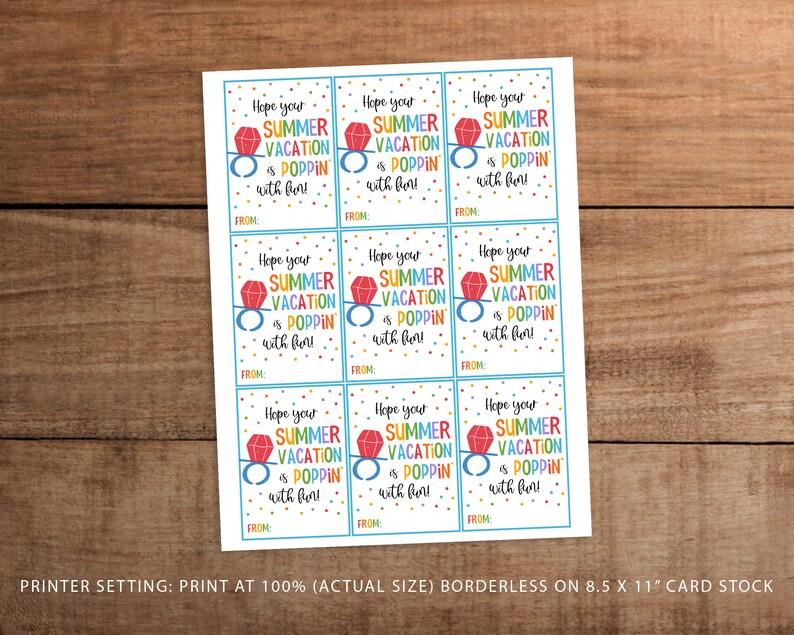 May include: A sheet of gift tags with the text "Hope your SUMMER VACATION is POPPIN' with fun!" in colourful letters. Each tag features a ring graphic with a red gem. The tags are on a wooden surface.